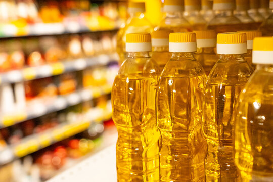 Clear Plastic Bottles of Edible Oil on a Grocery Store Shelf Surrounded by Colorful Products and Items in a Retail Environment