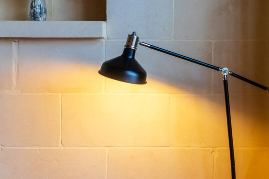 Black Adjustable Desk Lamp Casting Warm Light on Textured Stone Wall in Cozy Interior