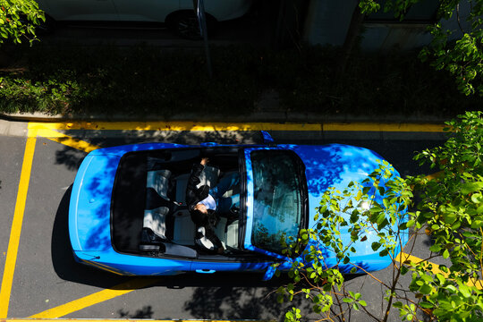 A stylish Asian girl sleeps inside a blue convertible.