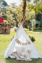 Children's teepee tent with teddy bear in a sunny garden © Marco