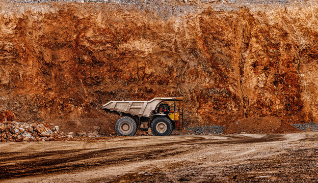 Single haul truck inside quarry against steep golden ore face for industrial background and mining equipment banner design