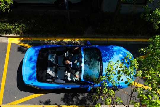 A stylish Asian girl sleeps inside a blue convertible.