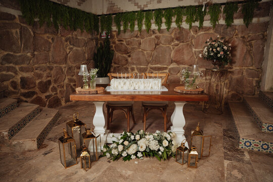 White cake with candles next to elegant floral decorations.