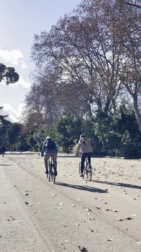 Dos ciclistas en bicicleta pedaleando en pareja dos dando pedales a couple of cyclists rider riding on bicycle pedalear al aire libre por avenida parque
