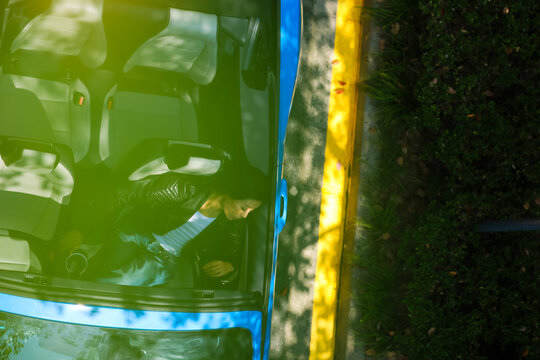 A stylish Asian girl sleeps inside a blue convertible.