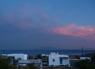 Beautiful clouds at sunset, in the foreground houses of traditional Cycladic architecture Mykonos island, Greece © Alika