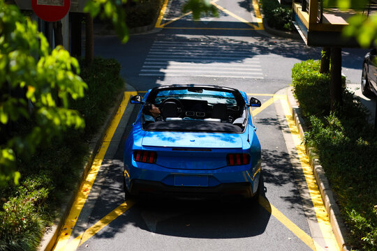 A stylish Asian girl sleeps inside a blue convertible.