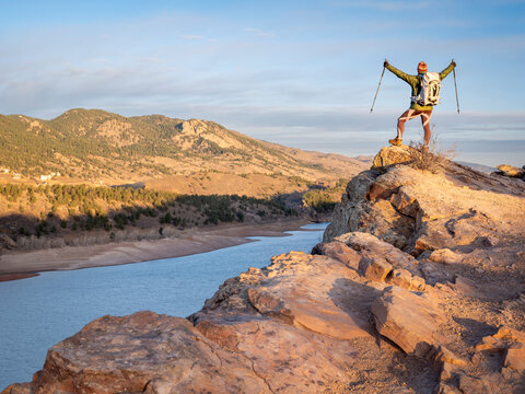 male hiker on a cliff overlooking Horsetooth Reservoir, popular recreation destination for boating, hiking and biking in northern Colorado, fall scenery at sunrise