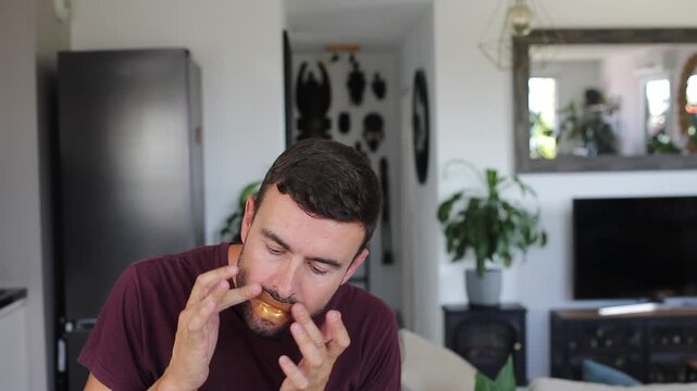Handsome adult man applying funny golden lip mask