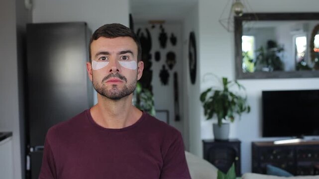 Handsome adult man applying cosmetic under eye patches