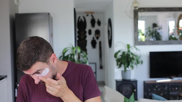 Handsome adult man applying cosmetic under eye patches
