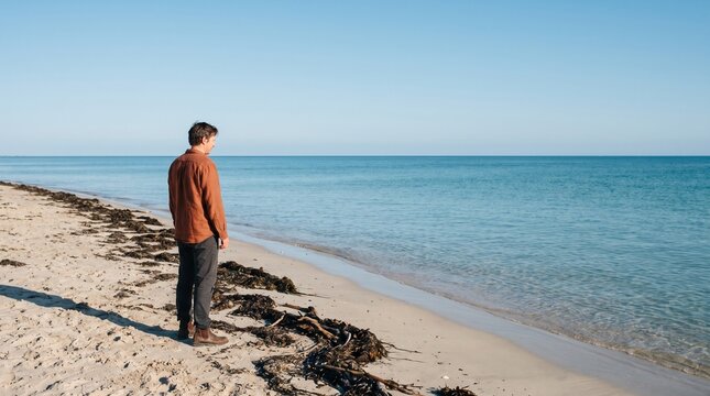 Solitary Beach Walker at High Water Mark Along Vivid Blue Shoreline