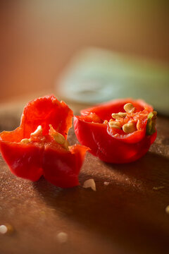 cut red chili pepper on wooden cutting board, spicy habanero halves showing seeds and flesh in macro close-up, soft focus with copy space, spicy culinary ingredient