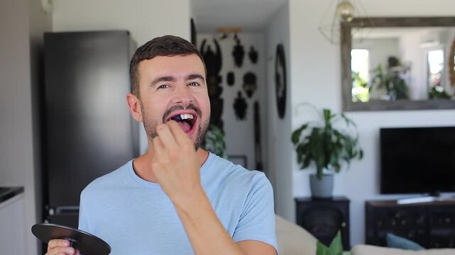 Smiling adult man applying blue teeth whitening strips