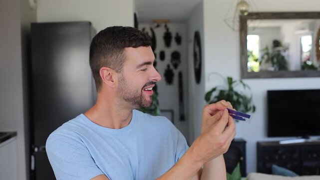 Smiling adult man applying blue teeth whitening strips