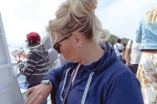 Blonde woman looks at her smart watch for notifications and the time, while out on a boat