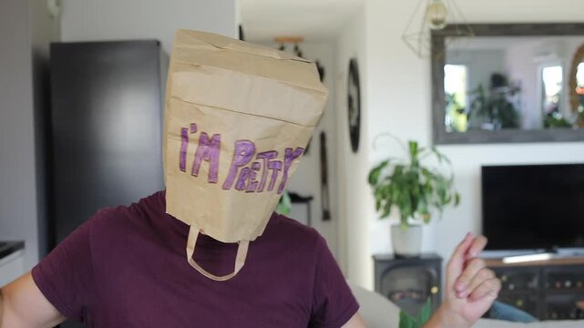 Person with 'I'M PRETTY' paper bag over head