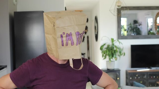 Man covering his natural beuty with a paper bag where he wrote "I&acute;m pretty"