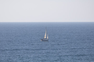 Fototapeta premium Lonely Sailboat Sailing on the Calm Blue Mediterranean Sea