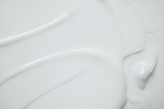 White cosmetic lotion texture creating abstract waves and soft peaks on clean background
