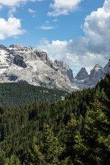 Fototapeta premium Dolomite mountain peaks above evergreen forest under dramatic clouds in Italy