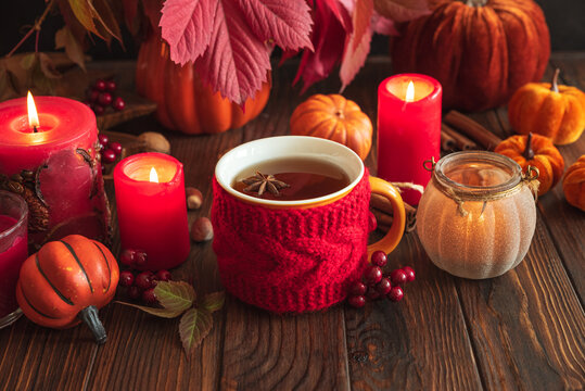 Hot tea with star anise among autumn decorations and burning candles