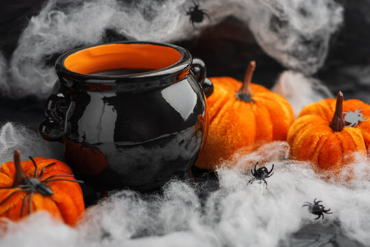 Halloween cauldron with pumpkins, spiders and cobwebs