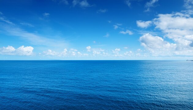 an expansive tranquil ocean meets the blue sky filled with fluffy white clouds capturing the peaceful serenity of the natural seascape on a clear day
