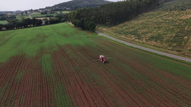 Agricultural tractor applying pesticide or fertilizer to young corn crops