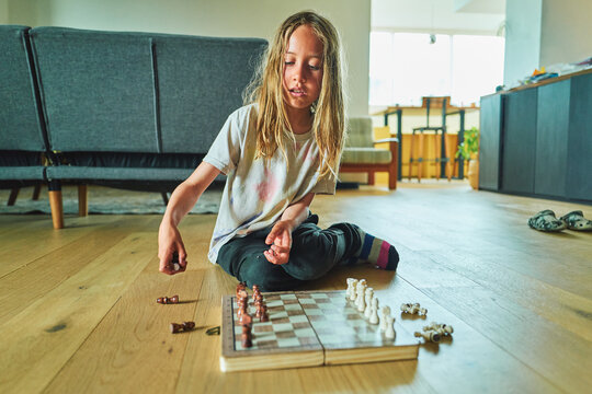 Boy setting up chess pieces on a board on the floor
