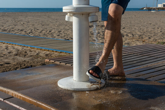 Man washing feet at public beach shower after swimming