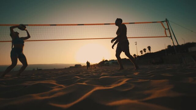 Silhouette of people playing beach volleyball at sunset