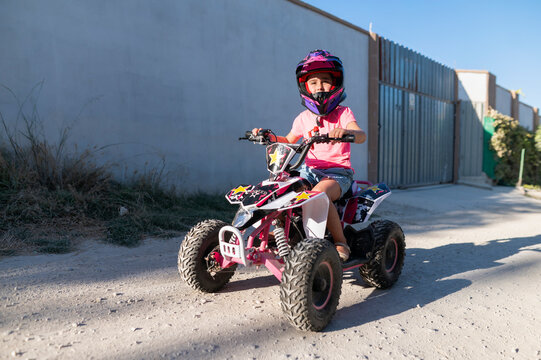 Young girl driving a quad bike on a dirt road