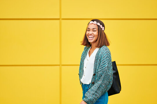 Woman laughing with flower crown and yellow background