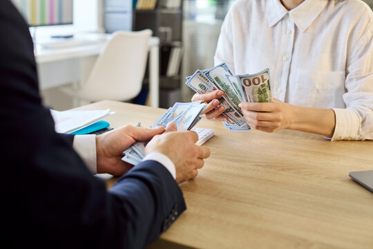 Employee receiving cash salary from manager in office. Close view of hands exchanging bills at a desk as payroll is paid, showing wages, payment and finance. Payroll and payday theme clear.