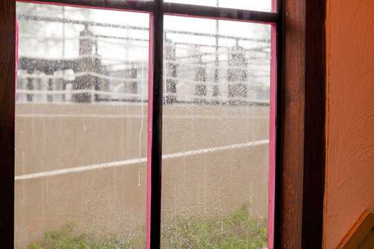 Raindrops trickle down the glass,Water Droplets on a pane of glass with blurred city background,View from a window showing rain falling rainy day,Copy space.