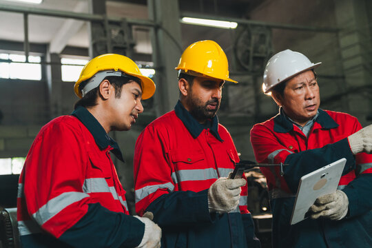 Engineer worker helmet factory clipboard inspection safety teamwork uniform industry group of male worker red uniform and hard hat reviewing clipboard during serious industrial inspection inside