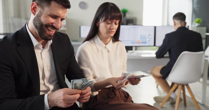 Employees coworkers in office compare wages. Smiling man counts money while woman gets less, showing payroll disparity, inequality, unfairness in office. Concept shows salary inequality at work.