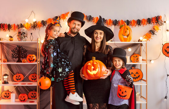 Portrait of happy family with kids celebrating halloween party at home, holding pumpkin together for fun in a festive setting filled with joy and excitement every year with laughter.