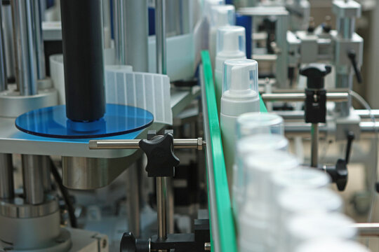 A conveyor belt for the production of cosmetics. White plastic bottles without labels. Cosmetics production