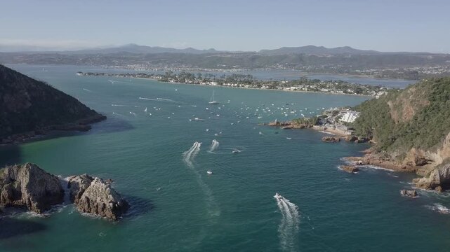 Aerial view of boats speeding across a scenic bay with rocky shoreline