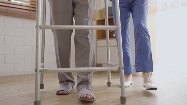 Health insurance with caregiver at home Walker Senior Caregiver Rehabilitation Leg Foot Indoor Clinic Support Mobility Assistance Elderly Patient Using Mobility Aid During Recovery Scene