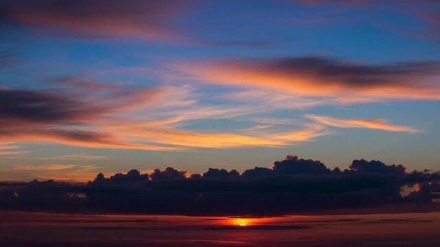 Vibrant sunset occurs over serene landscape with trees and sky
