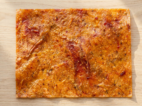 Square sheet of dehydrated fruit leather on a wooden table