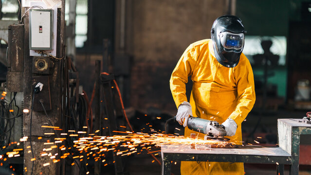 Metal worker grinder spark welding factory protective helmet glove industry, metal worker with grinder spark in factory wearing protective helmet and glove during industrial fabrication process