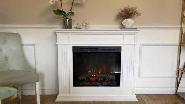 Horizontal 4K video of a modern classic living room interior with a handmade white electric fireplace, elegant wall molding, and stylish decor
