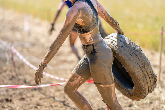 Female athlete carrying a heavy tire during mud obstacle race