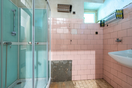 Abandoned retro pink tiled bathroom with shower and sink