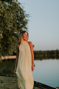 Woman walks by the water during sunset wearing a light dress at a lakeside location