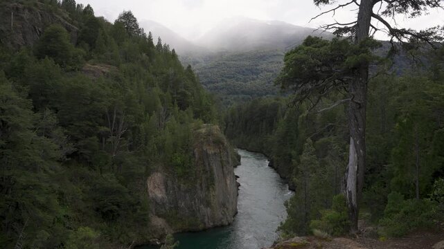 Futaleufu River winding through a deep forest canyon, surrounded by lush green trees and snow-capped mountains in Patagonia, Chile.